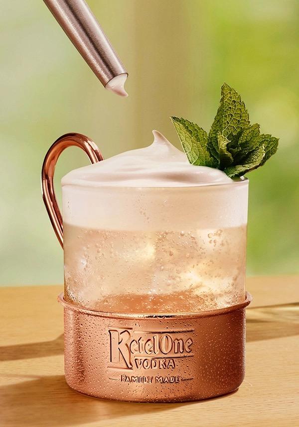 Ketel One Brazil Mule in Glass Mug with hand adding cream 