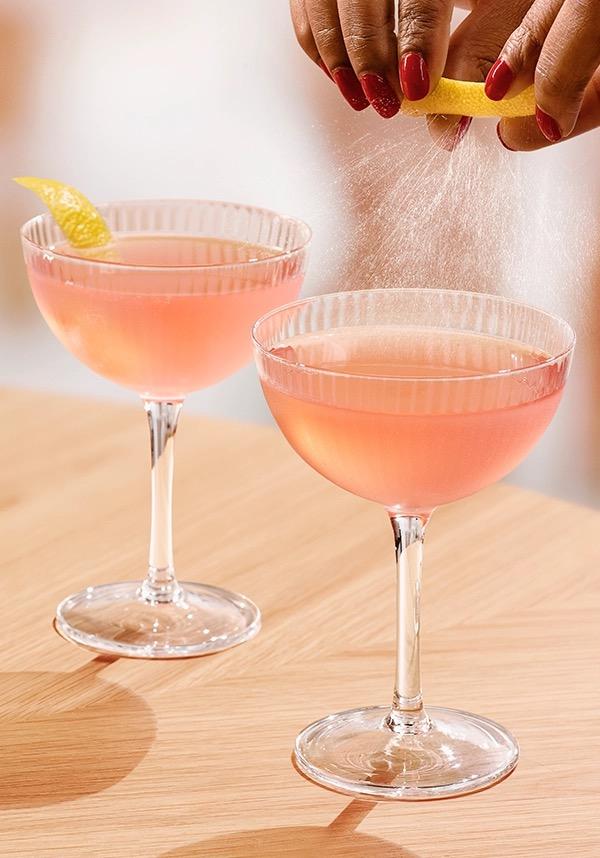 Ketel One Cosmo in Coupe Glass with hand adding lemon spritz