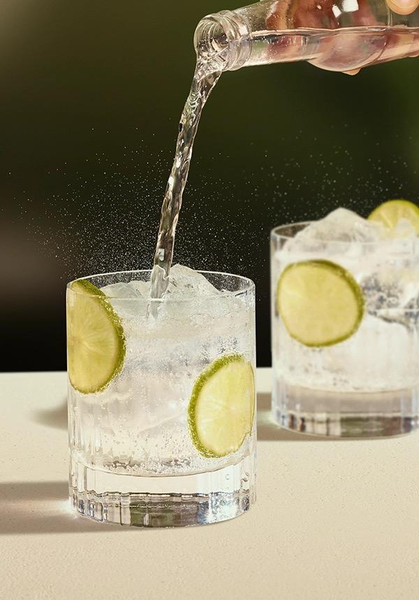 Ketel One Vodka Tonic in Rocks Glass with hand adding tonic