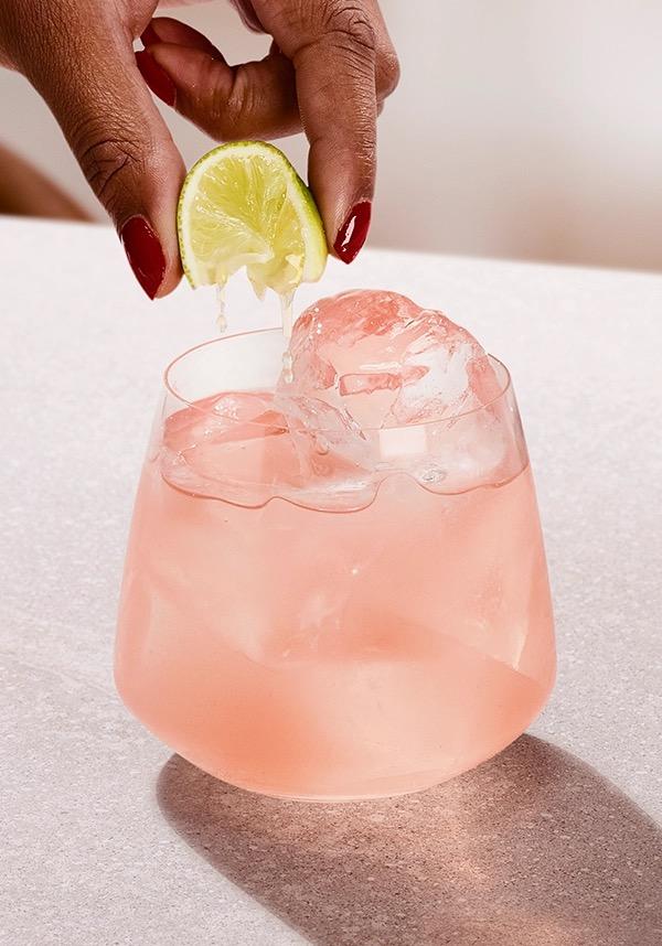 Ketel One Sea Breeze in Rocks Glass with hand adding lime spritz