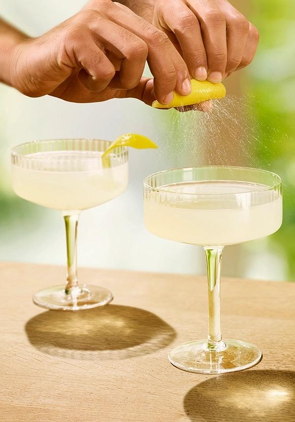 Ketel One Lemon Drop Martini in Coupe Glass with hand adding lemon spritz
